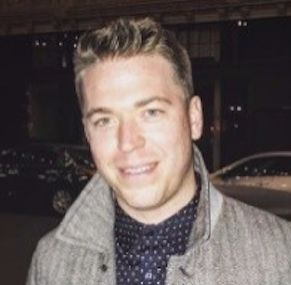 A man in a jacket and tie smiling for the camera.